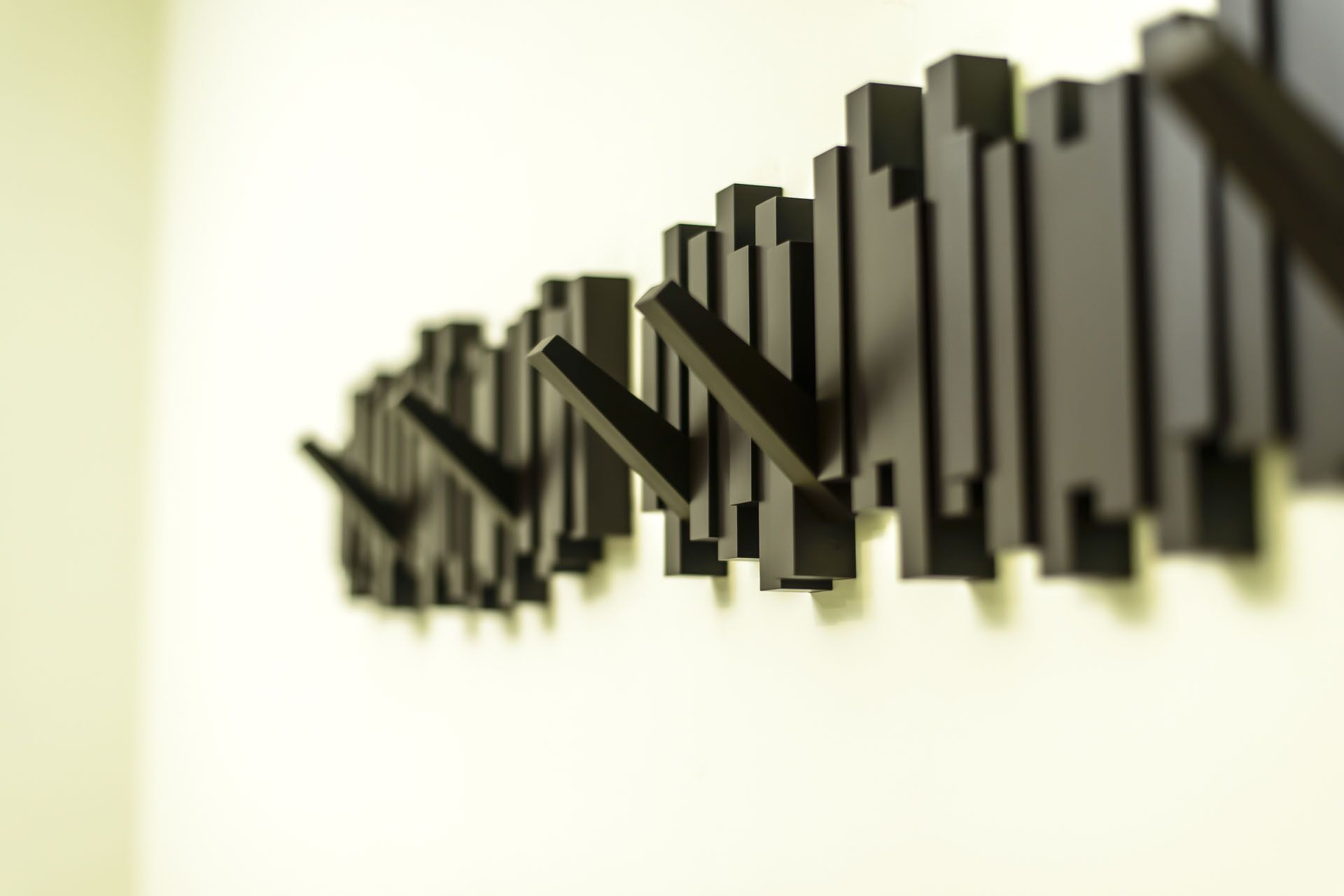 A modern, abstract sculpture with a series of black, rectangular shapes arranged in a staggered pattern against a light background.