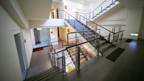 Un interior de varios niveles con una escalera central, barandas de vidrio y un diseño moderno.