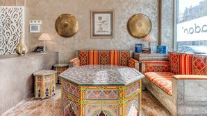 Una habitación con un sofá estampado, una mesa de centro decorativa y una lámpara fijada a la pared.