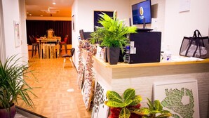 A reception area with a wooden desk, a computer, a television, and several potted plants. - 88HOTELS (Matsuyama)