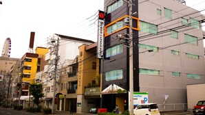 A modern hotel with multiple floors, a visible entrance, and a parking sign. - 88HOTELS (Matsuyama)
