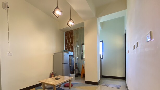 A modern kitchen with a refrigerator, a wooden table, and a patterned rug. - B'Fin Hostel Lanyu (Lanyu)