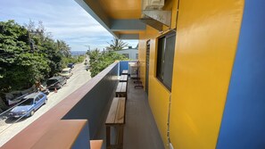 A balcony with wooden benches and a view of a street with parked cars and greenery. - B'Fin Hostel Lanyu (Lanyu)