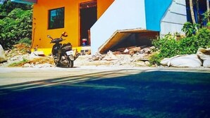 A building with a partially collapsed roof, a parked motorcycle, and a clear blue sky. - B'Fin Hostel Lanyu (Lanyu)