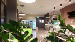 A modern interior with a bar area, seating, and a green plant in the foreground. - Hotel Puldin COOP (Plovdiv)