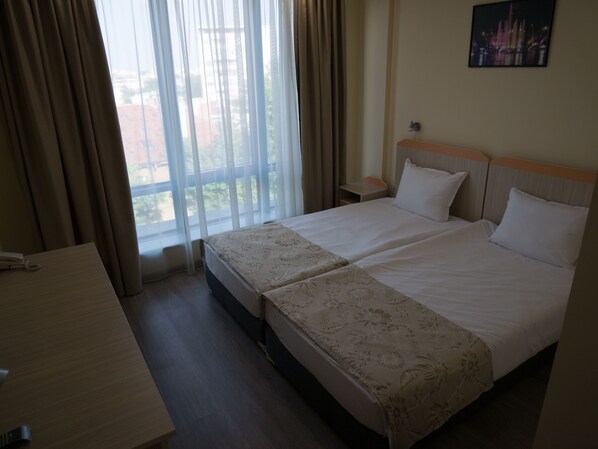 A hotel room with a large bed, a desk, and a view of the outdoors. - Hotel Puldin COOP (Plovdiv)