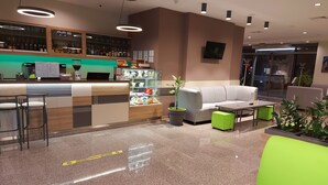 A modern lobby with a bar area, seating, and a green plant. - Hotel Puldin COOP (Plovdiv)