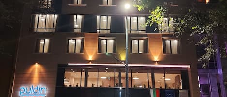 Un hotel con fachada moderna, amplias ventanas y un cartel llamativo que dice 'pulcin coop hotel'.