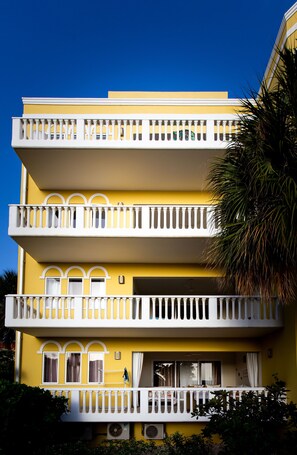 A multi-story yellow building with white balconies and air conditioning units.
