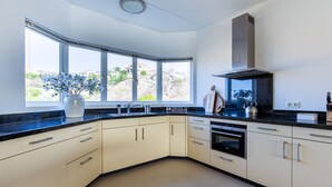 A modern kitchen with a large window, built-in oven, and stainless steel appliances.