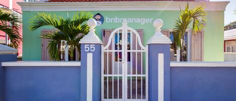 A building with a gated entrance, a sign reading "bnbmanager", and the number "55" on the gate.