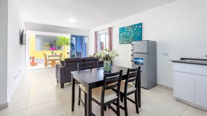 Eine moderne Küche mit Essbereich, einem Kühlschrank und einem Fenster mit Vorhängen.