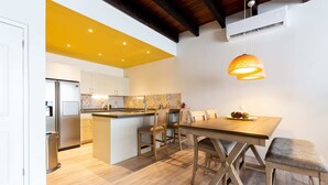 Una cocina moderna con una isla central, sillas de madera y una lámpara colgante.
