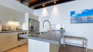 Una cocina moderna con una isla integrada, electrodomésticos de acero inoxidable y un amplio ventanal con vistas a la ciudad.
