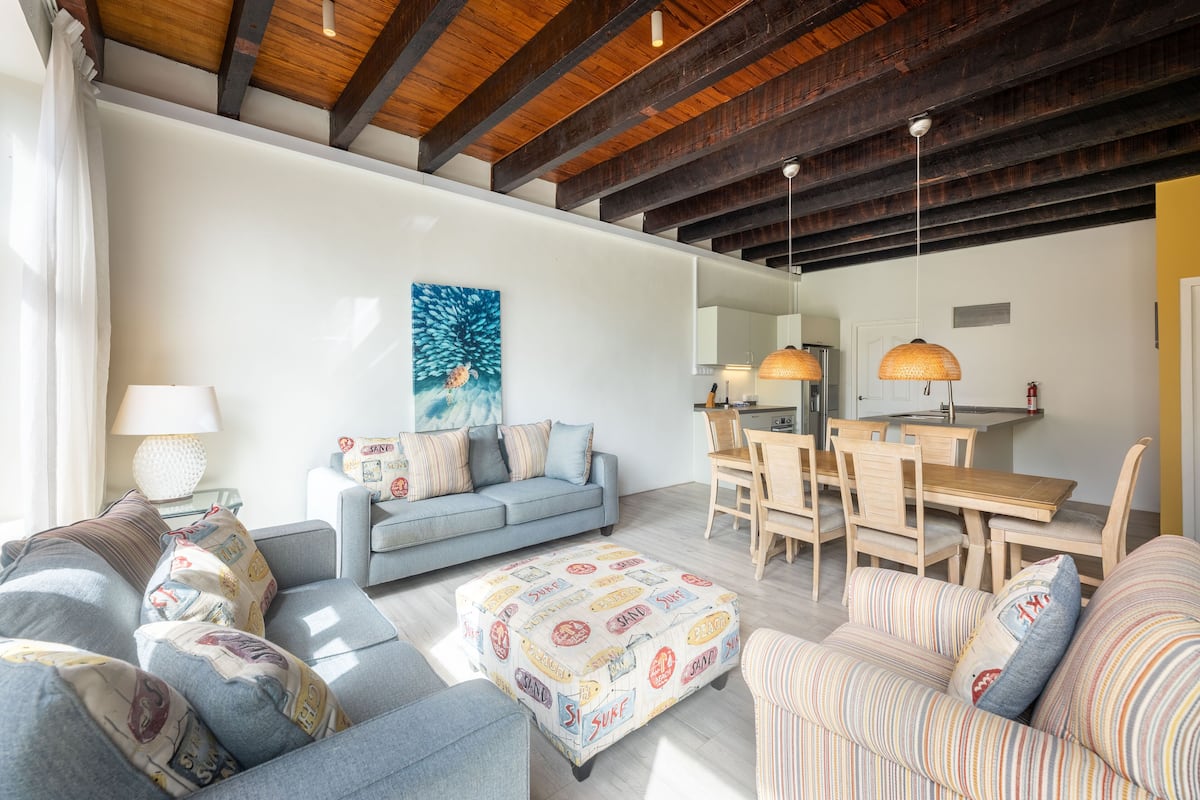 A spacious living room with a high ceiling, a dining area, and a kitchen.