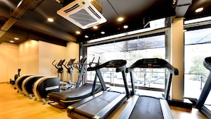 A gym with treadmills, ellipticals, and stationary bikes arranged in a row.