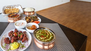 A table with various dishes, including rice, curry, and meat, in front of a wall with 'BANGALORE' text.