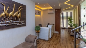 A reception area with a modern design, featuring a reception desk, a seating area, and a wall-mounted artwork of stylized birds.