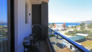 A balcony with a table and chairs, overlooking a coastal area with buildings and a clear sky. - Hotel Citrus (Ksamil)