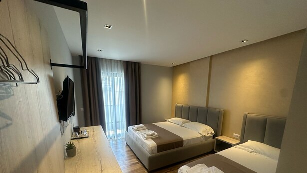 Une chambre d’hôtel moderne avec deux lits, un bureau en bois et une grande fenêtre avec des rideaux.