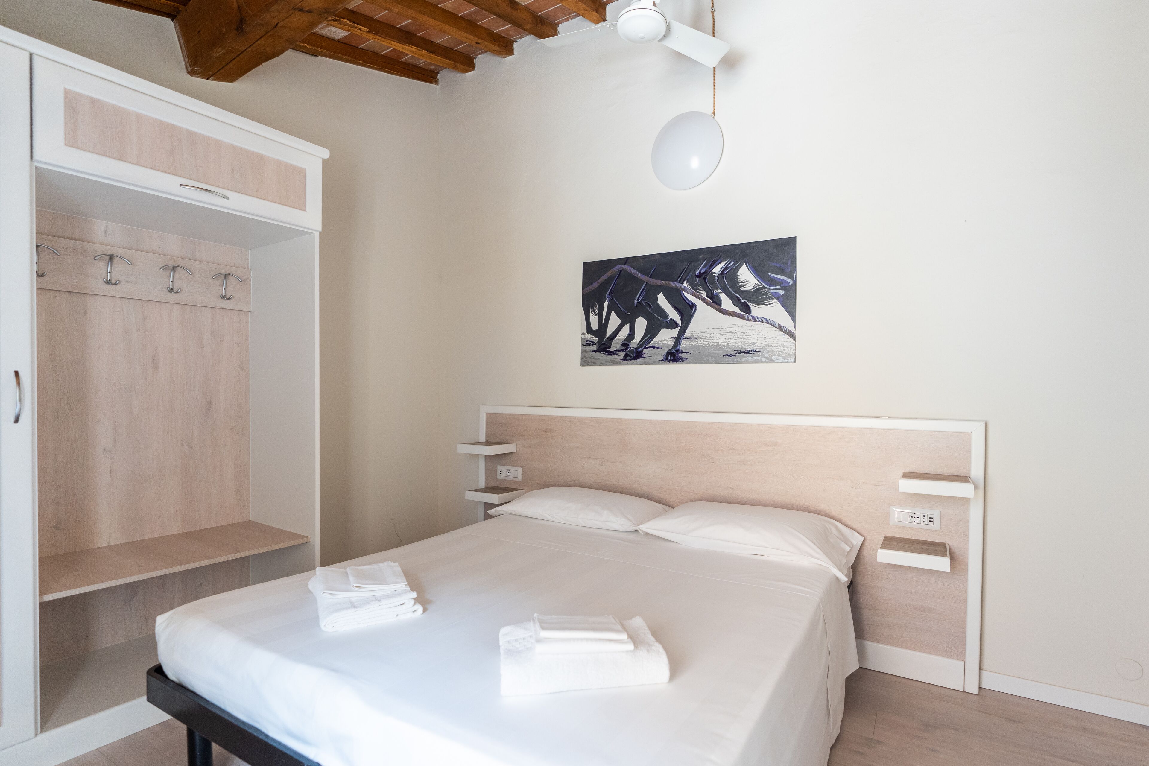 Un dormitorio con cama, armario, un cuadro y ventilador de techo.
