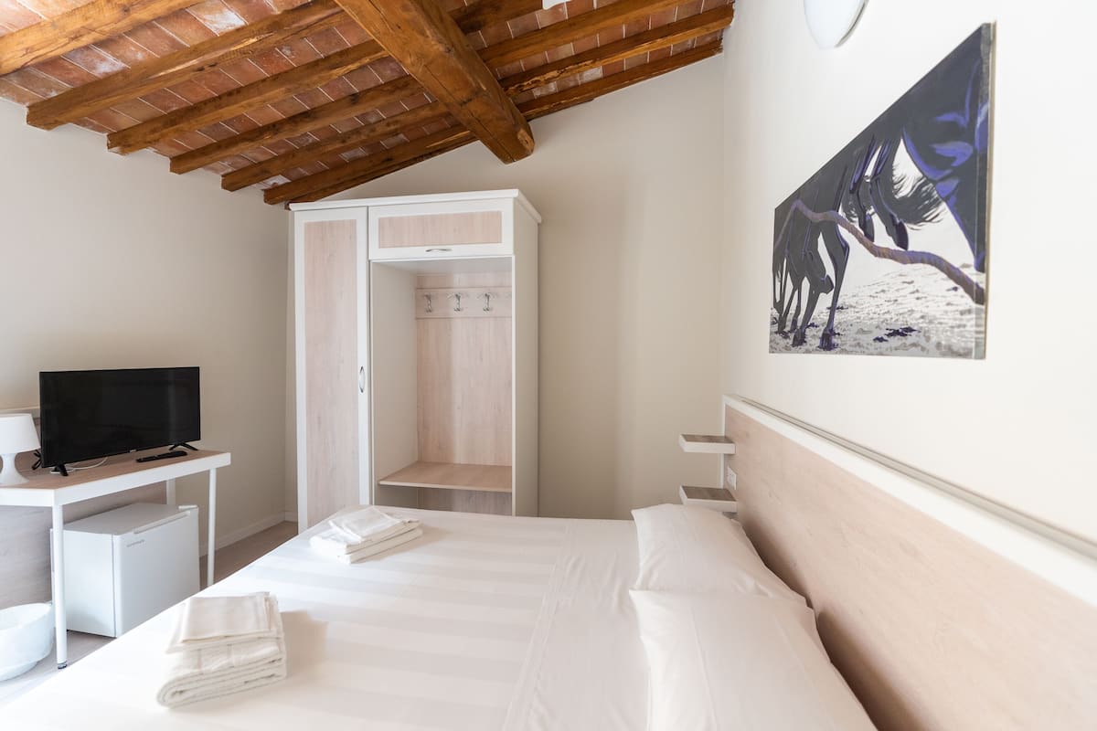 A bedroom with a bed, a TV, a desk, and a wardrobe.
