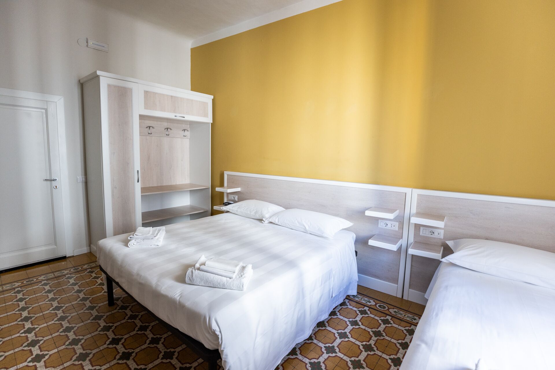 Ein Hotelzimmer mit Bett, Kleiderschrank und Nachttisch.