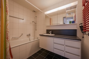 A modern bathroom with a bathtub, a sink, and a mirror.