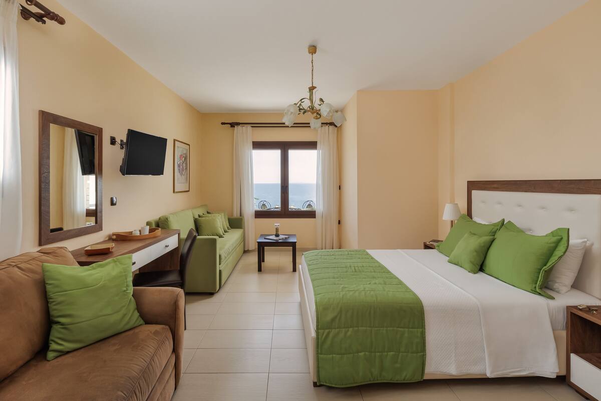 Een hotelkamer met een bed, een slaapbank, een bureau en een raam met uitzicht.