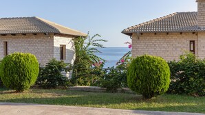 Un barrio residencial con dos casas de ladrillo, vistas despejadas al mar y vegetación bien cuidada.