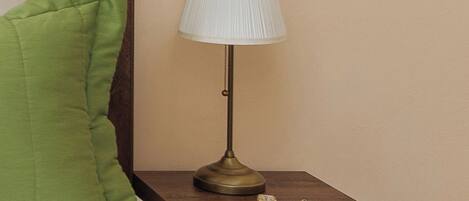 A bed with a green pillow and a bedside table with a lamp.