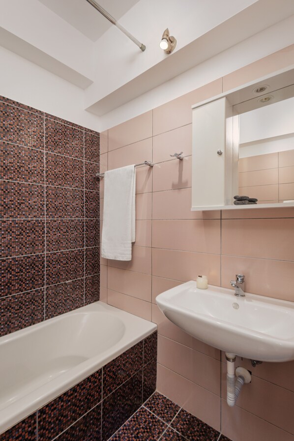 A bathroom with a bathtub, sink, and mirror. - Costa Smeralda (Igoumenitsa)