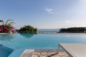 Una piscina azul cristalina con vistas al mar y una isla distante.