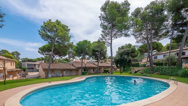 Une piscine entourée d’une terrasse carrelée, où une personne nage.