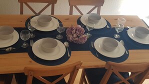 A dining table set with plates, bowls, wine glasses, and cutlery, surrounded by wooden chairs. - Cyrus House Thameside (London)