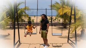 A beach swing set with a person and a child. - Aborigines beach resort (Keta)