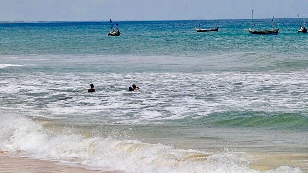 A beach with calm waters, boats, and two people swimming. - Aborigines beach resort (Keta)