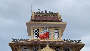 Un edificio tradicional con una imponente torre del reloj y una bandera.