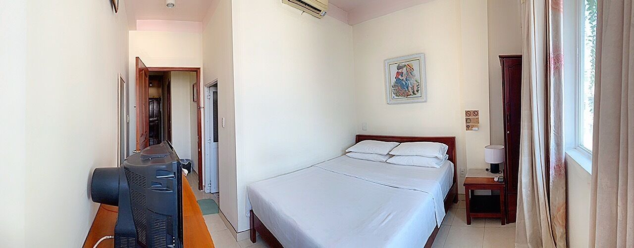 Une chambre d’hôtel avec un lit, une télévision, une table de chevet et une fenêtre avec des rideaux.