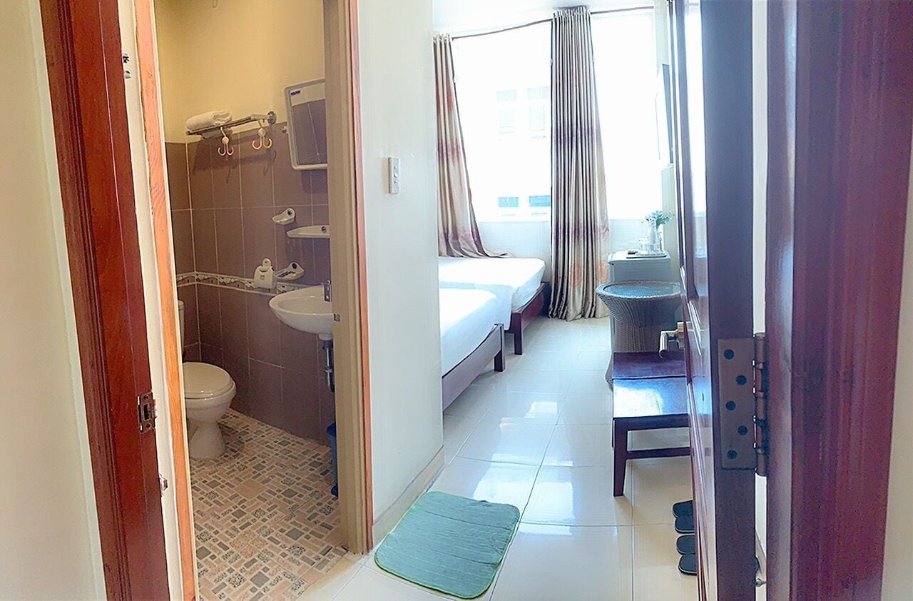 A hotel room with a bathroom, a bed, and a small table with a plant.