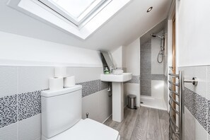 A modern bathroom with a skylight, a toilet, a sink, and a shower. - Prestige STAY Aparthotel Cavern Quarter (Liverpool)