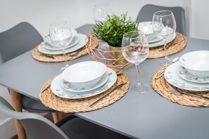 A dining table set with white plates, silverware, and wine glasses, accompanied by woven placemats and a small potted plant. - Prestige STAY Aparthotel Cavern Quarter (Liverpool)