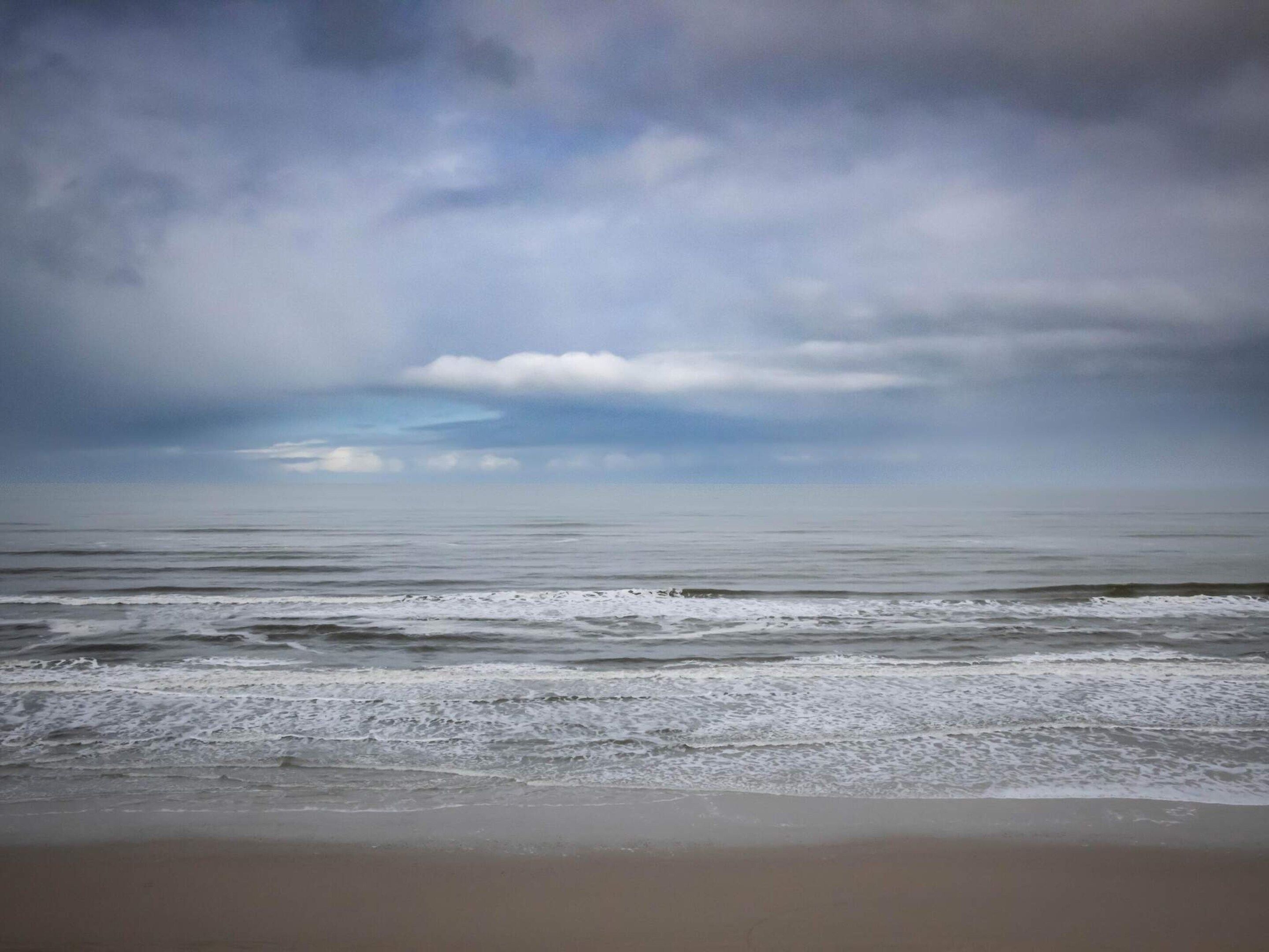 A beach with waves and a cloudy sky.