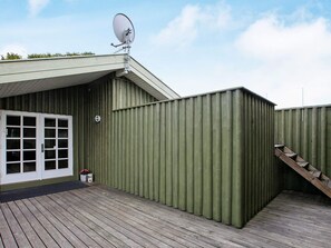 A building with a satellite dish, a door, and a wooden deck.