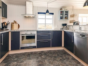 Una cocina moderna con armarios oscuros, horno Bosch, lavavajillas Siemens y piso con estampado de piedra.