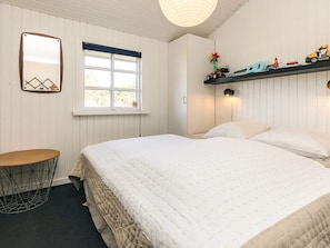 A bedroom with a bed, a round table, a window, and a shelf with toys.