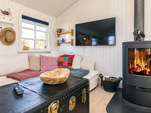 Een gezellige woonkamer met een bank, een televisie, een open haard en een raam met uitzicht.