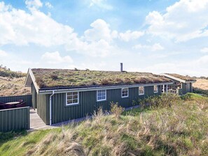 A green-roofed building with a wooden deck and a clear sky. - 4 Star Holiday Home in Lokken (Lokken)