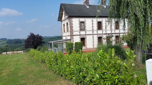 A large, two-story house with a brick facade and white trim, surrounded by lush greenery and a clear sky. - vacation home   (Hugleville-en-Caux)