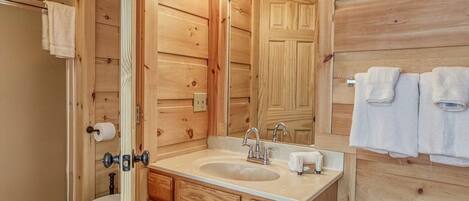 A wooden-paneled bathroom with a sink, mirror, and towel rack.